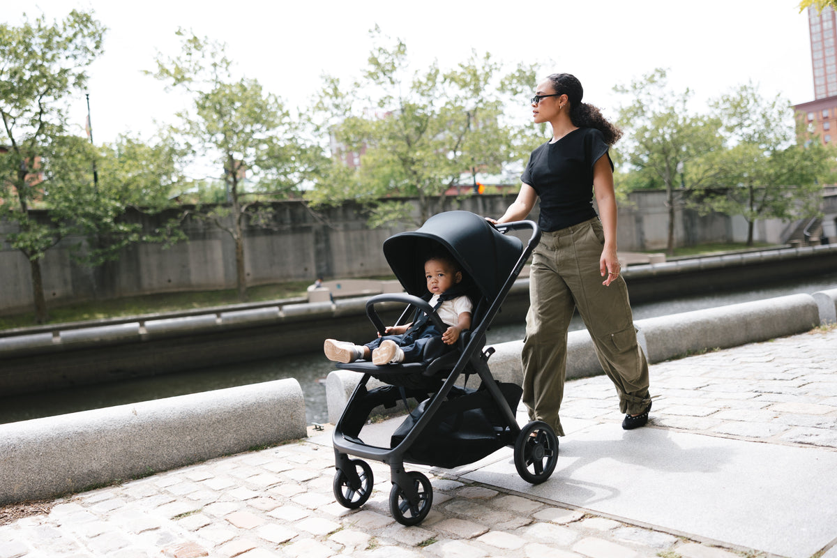 A parent pushing an UPPAbaby pram on a footpath