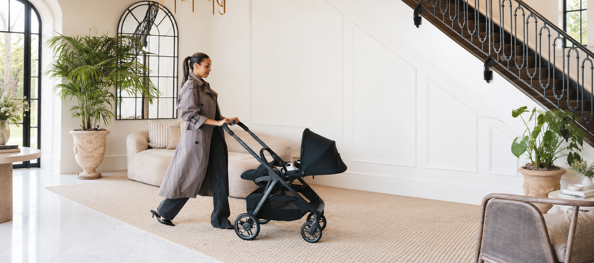 A parent pushing the UPPAbaby Kona through a bright living room