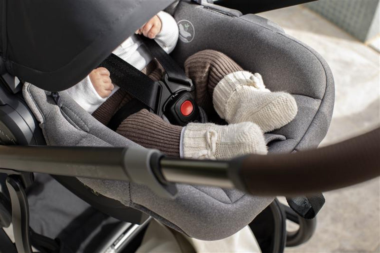 A newborn asleep in an UPPAbaby Mesa capsule clicked onto a Vista